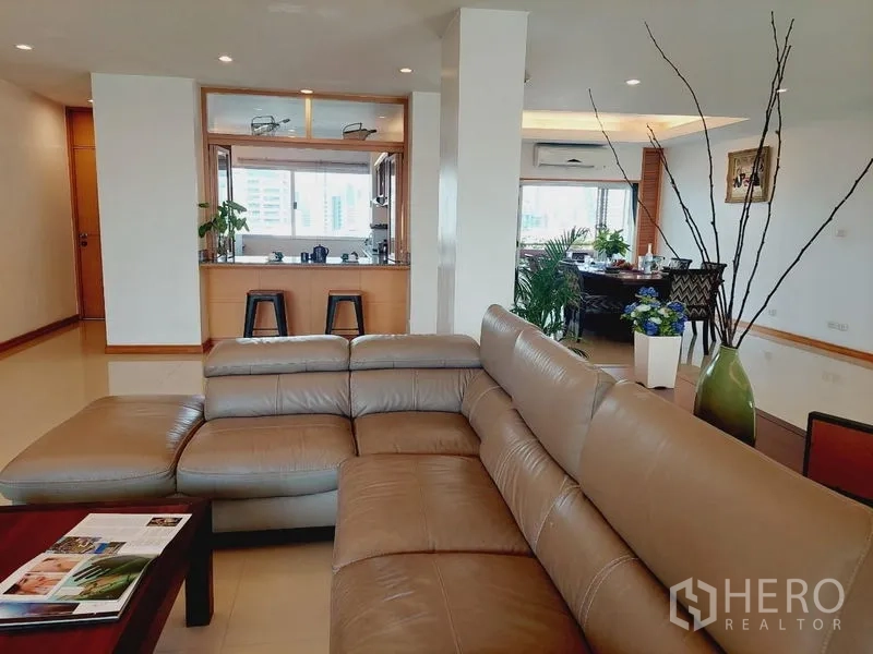 อพาร์ทเมนท์ ให้เช่า - โซนพักผ่อนแบบเปิดโล่ง โซฟาหนังตัวแอล มองเห็นช่องส่งอาหารจากครัว