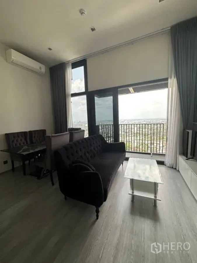 คอนโด ให้เช่าในPhra Khanong, Bangkok - ห้องนั่งเล่นโปร่งเพดานสูง หน้าต่างเต็มบานและระเบียงมองเห็นวิวสกายไลน์กรุงเทพฯ