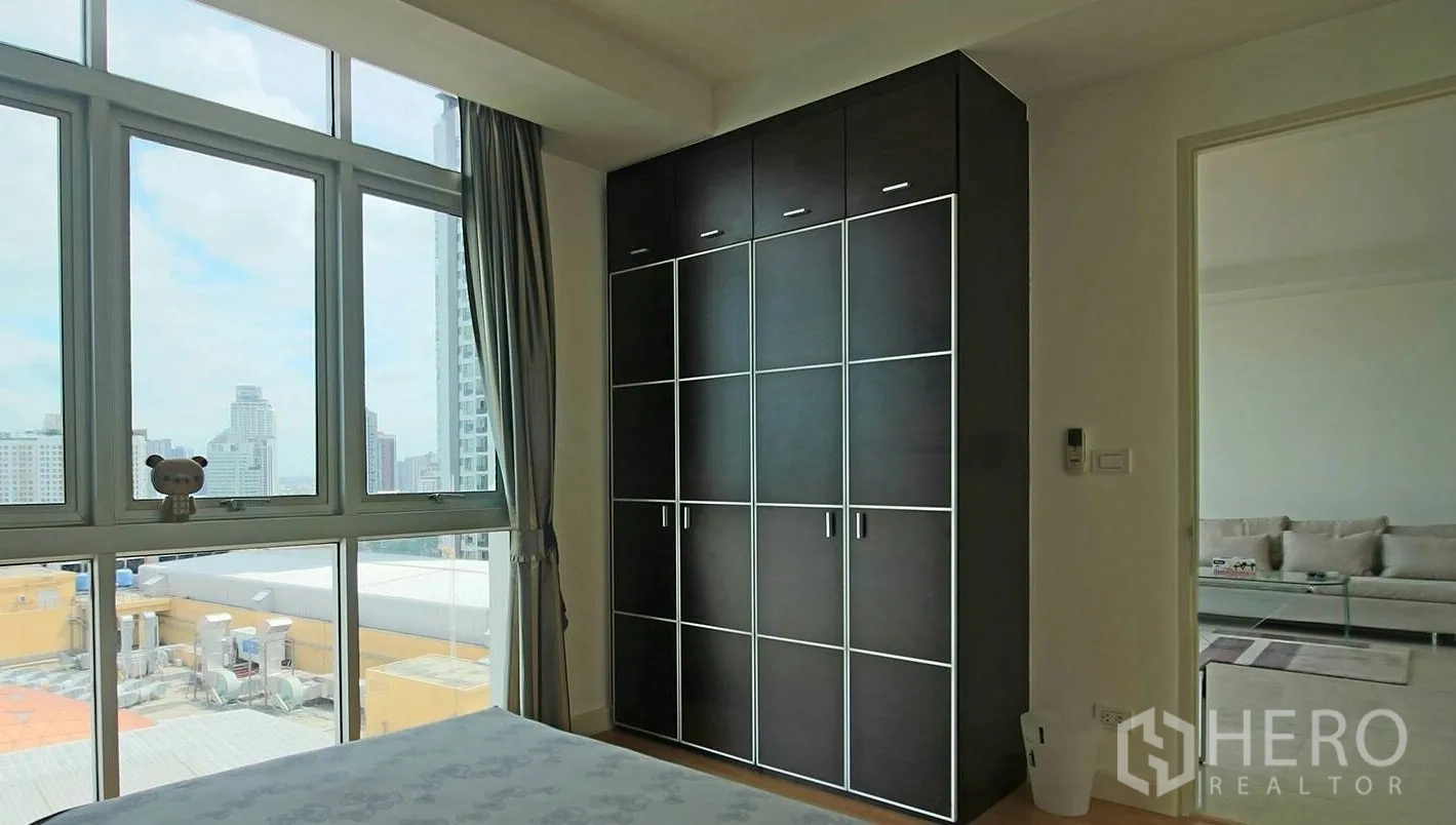 คอนโด ให้เช่าในKhlong Toei, Bangkok - ห้องนอนพร้อมหน้าต่างบานใหญ่และตู้เสื้อผ้าไม้สีเข้ม มองเห็นวิวเมือง
