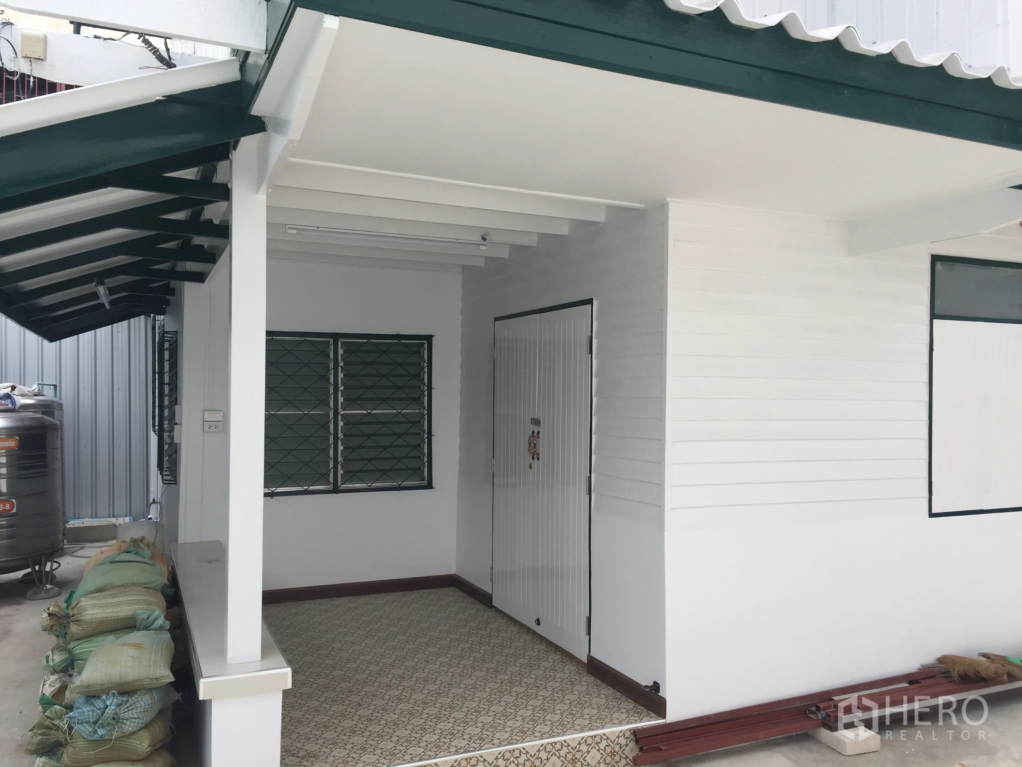 Detached House for rent in Bang Rak, Bangkok - Freshly painted house exterior with covered porch, barred windows, and green roof trim.