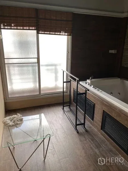 Townhouse for rent in Wang Thonglang, Bangkok - Bathroom with large jacuzzi tub beside a frosted window and glass side table.