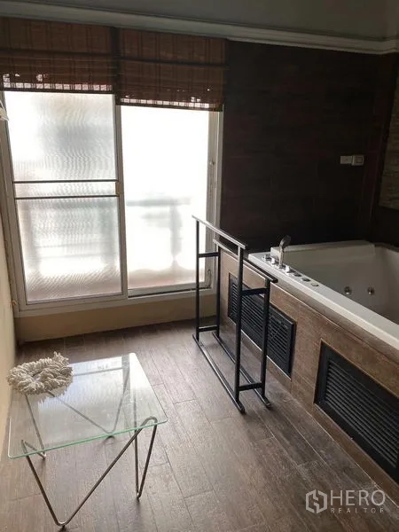 Townhouse for rent in Wang Thonglang, Bangkok - Bathroom with large jacuzzi tub beside a frosted window and glass side table.