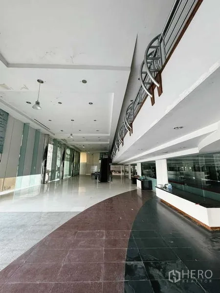 展厅 出租在Min Buri, Bangkok - 弧形大堂区域，双色地砖与吊灯，旁为落地玻璃。