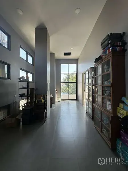 Home Office for sale in Lam Luk Ka, Pathum Thani - Bright hallway with floor-to-ceiling window, gray tile floors and display cabinets
