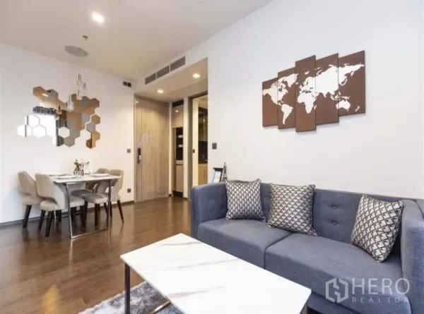 公寓 出租在Ratchathewi, Bangkok - 现代客厅，灰色沙发、云石茶几、墙面装饰与餐桌，木地板质感佳。