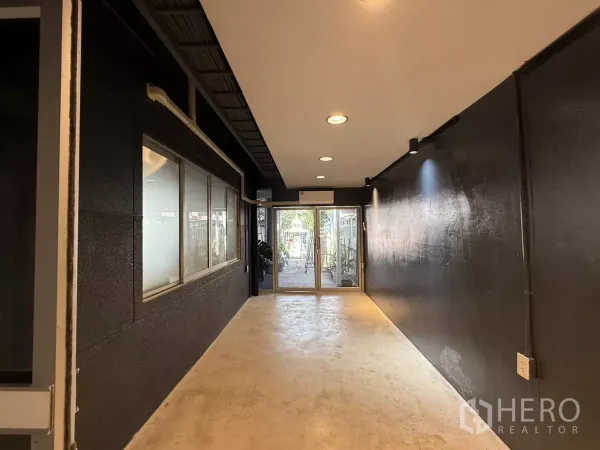 Office Space for rent in Wang Thonglang, Bangkok - Entrance hallway with black walls, recessed lights and a sliding glass door to the exterior.