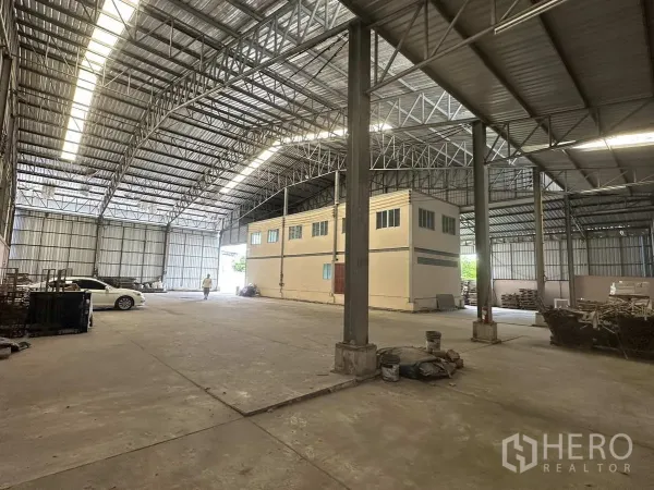 Factory for rent in Pathum Thani - Open production and storage floor with steel columns, loading access and natural light panels.