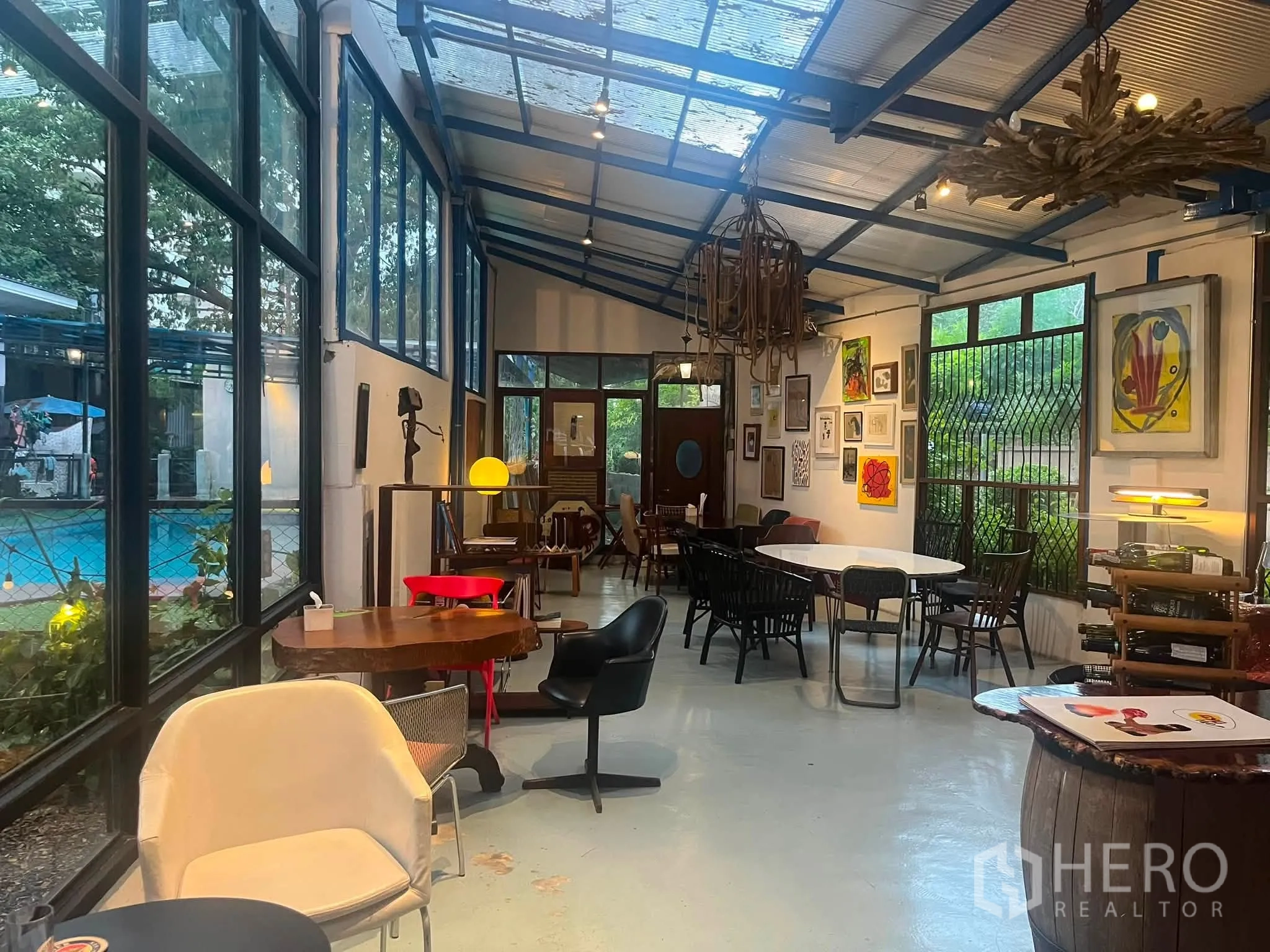 零售空间 for rent in Watthana, Bangkok - 狭长室内空间，采光屋顶与大窗，摆放多款桌椅与艺术装饰。