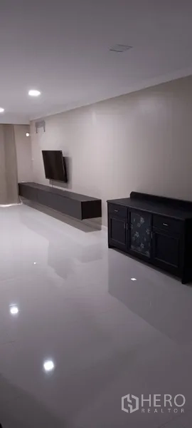 公寓 出租在Watthana, Bangkok - 宽阔客厅，电视背景墙与深色边柜，顶置筒灯。