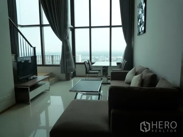 คอนโด ให้เช่าในKhlong Toei, Bangkok - ห้องรับแขกเพดานสูงโปร่ง ผนังกระจกเต็มบาน พร้อมชุดโต๊ะทานอาหารและวิวเมือง