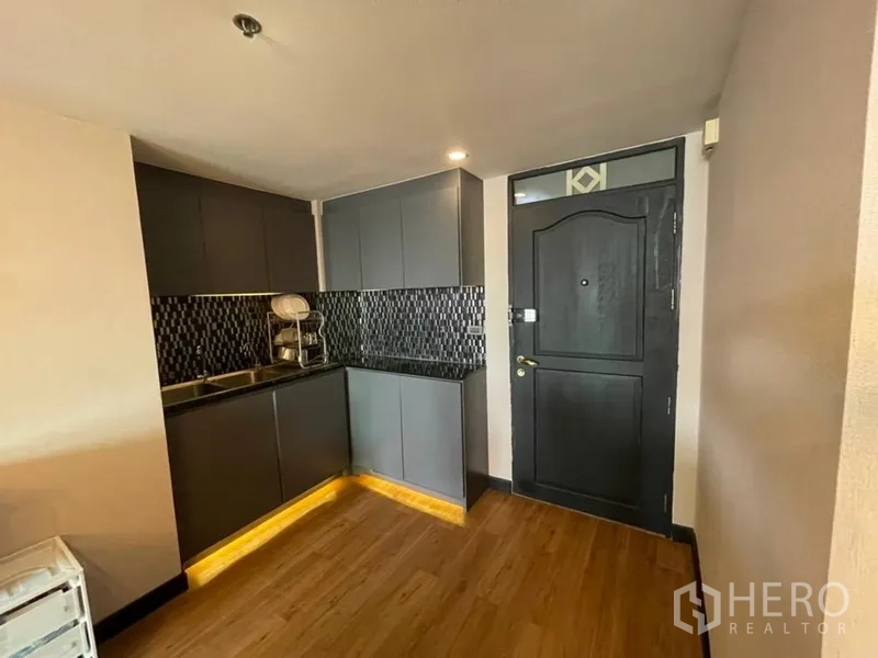 Condominium for sale in Chatuchak, Bangkok - Entry corner with L-shaped kitchen, black mosaic backsplash and double sink in a modern condo.