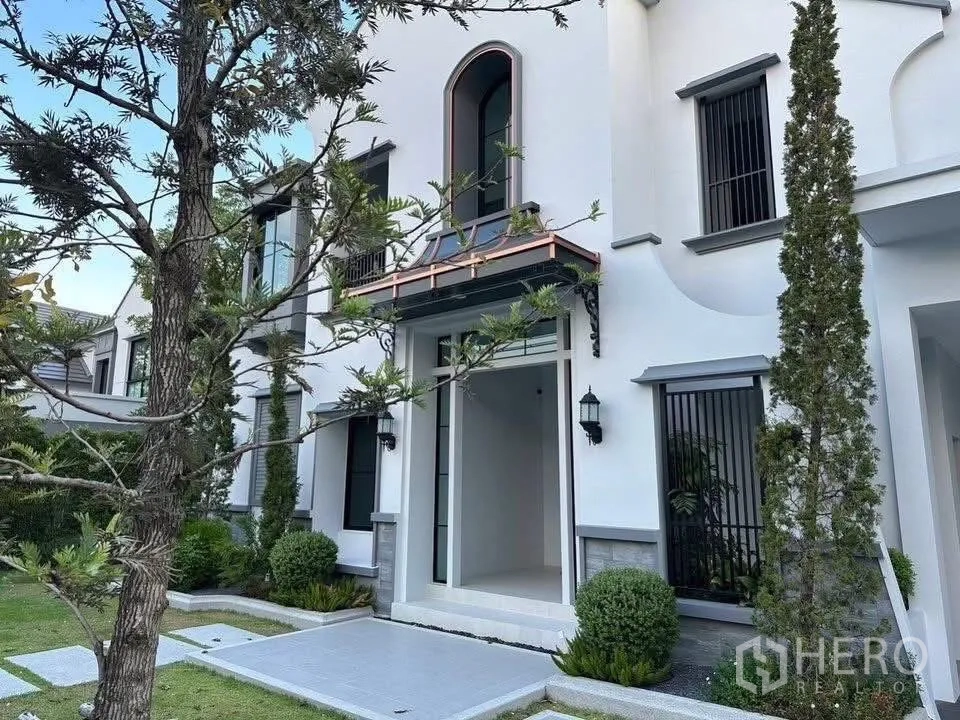 Detached House for sale in Taling Chan, Bangkok - Main entrance porch framed by tall windows, wall lanterns and a landscaped front yard.