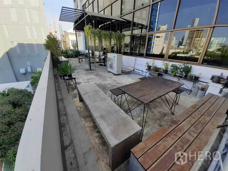 办公空间 出租在Khlong Toei, Bangkok - 室外露台设长椅与桌子，摆放绿植，临近玻璃幕墙可观城市景色。