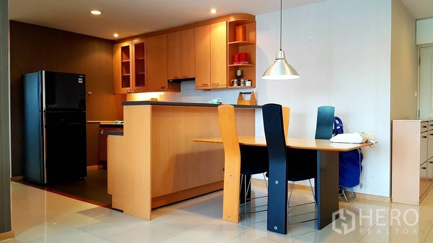 Condominium for rent in Khlong Toei, Bangkok - Open kitchen with wood cabinets, black refrigerator, breakfast bar and dining table.