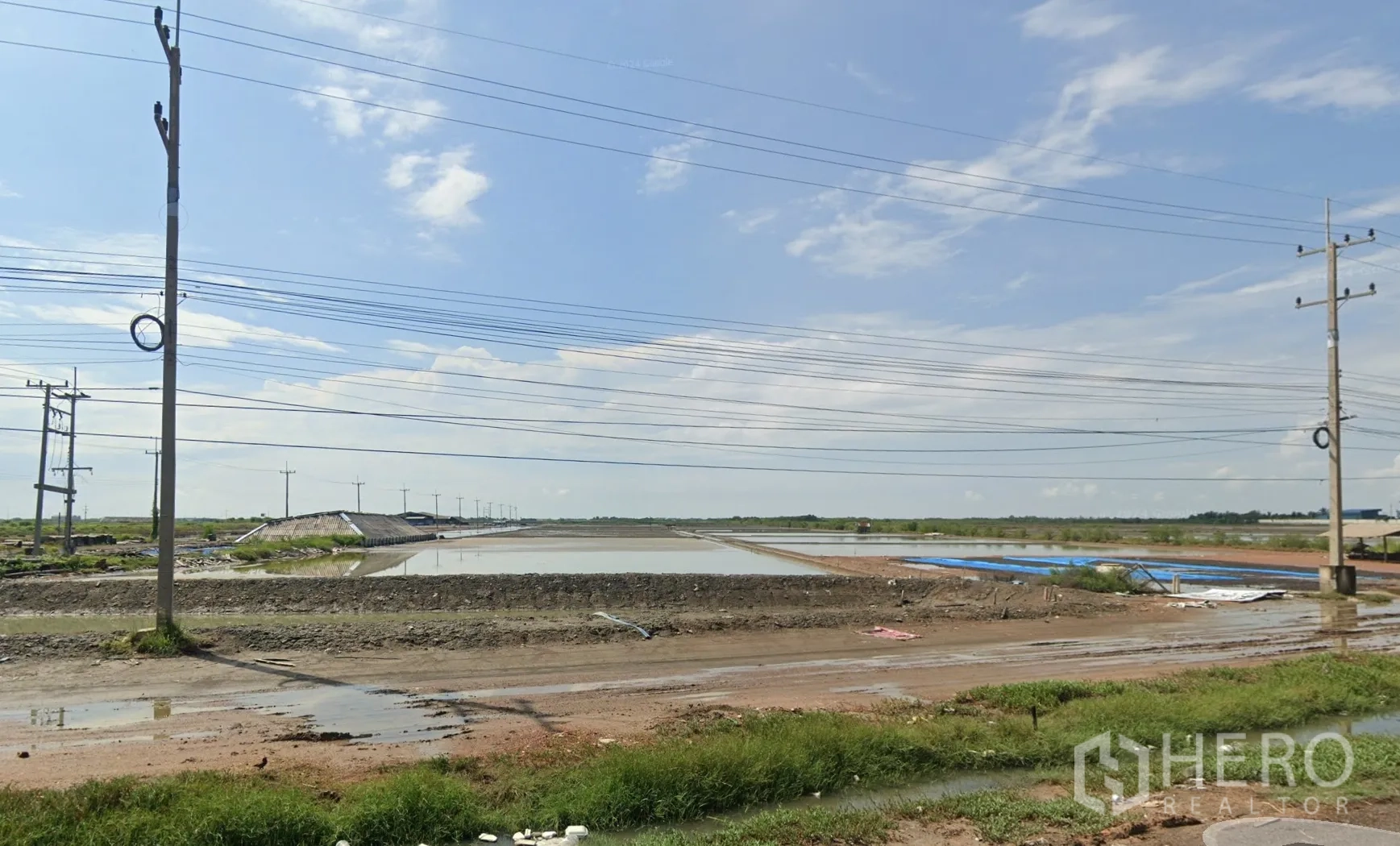 Land for sale in Mueang Samut Sakhon, Samut Sakhon - Open land parcels with shallow ponds, earth embankments, and overhead power lines by the road.