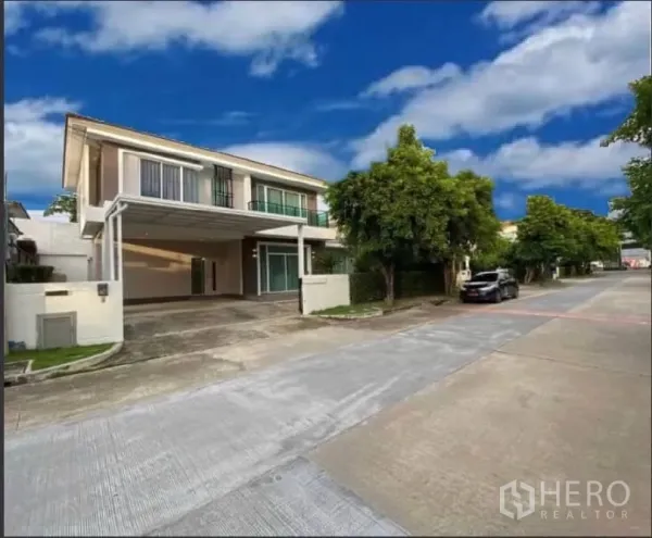 Detached House for rent or sale in Prawet, Bangkok - Modern two-storey detached house with a covered double carport and gated entrance on a quiet estate road.