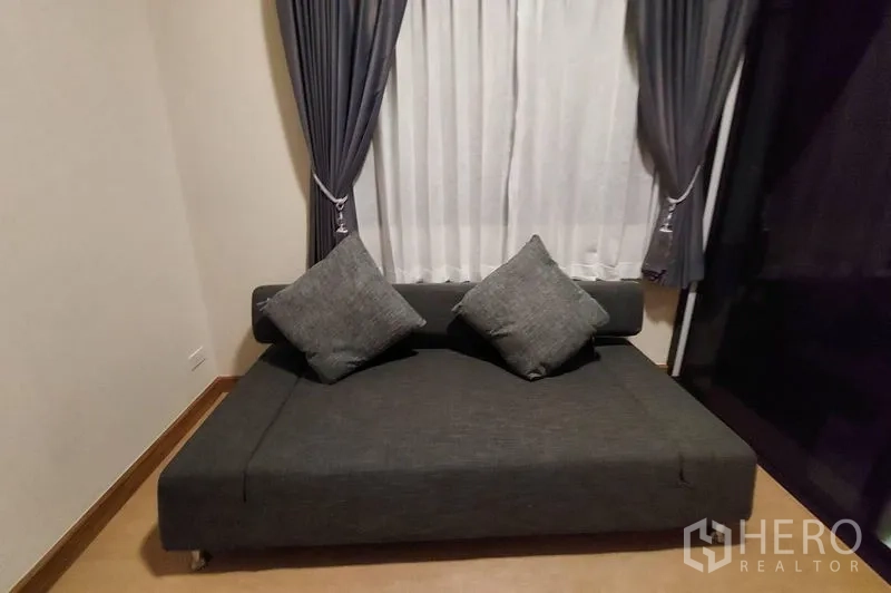 联排别墅 出租在Thanyaburi, Pathum Thani - 小型休闲角，深色沙发与整面窗帘