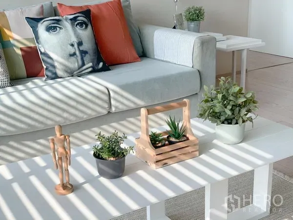 คอนโด ให้เช่าในWatthana, Bangkok - ห้องนั่งเล่นรับแสง พร้อมโซฟาสีเทา หมอนลายศิลป์ และโต๊ะกลางสีขาววางต้นไม้