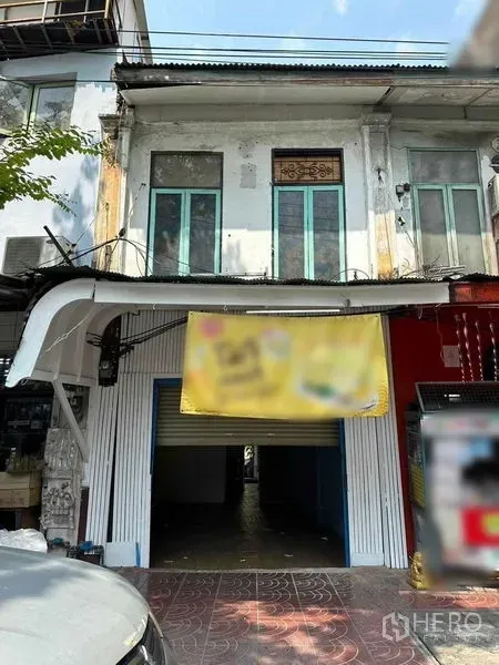Shophouse for rent in Samphanthawong, Bangkok - Two-storey shophouse exterior with tall green-framed windows, street-level rolling shutter and covered entrance.