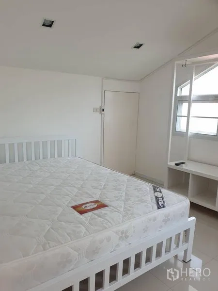 Detached House for rent in Khlong Toei, Bangkok - Bright guest bedroom with white bed frame and built-in shelving.