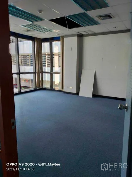 办公空间 出租在Watthana, Bangkok - 明亮转角工位，近 Asok，落地窗、蓝色地毯与城市景观。