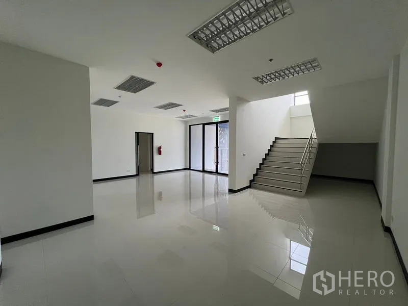 Warehouse for rent in Chon Buri - Ground-floor office lobby with staircase, glossy tiled floor and glass entrance.