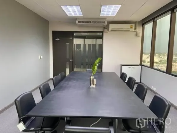 办公空间 出租在Bang Na, Bangkok - 会议室配长桌与黑色座椅，分体空调与磨砂玻璃门。