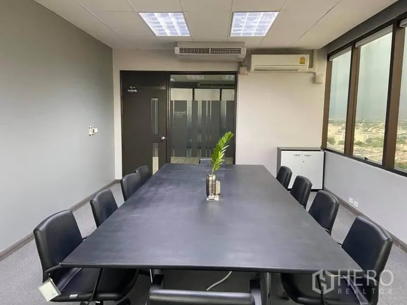 办公空间 出租在Bang Na, Bangkok - 会议室配长桌与黑色座椅，分体空调与磨砂玻璃门。