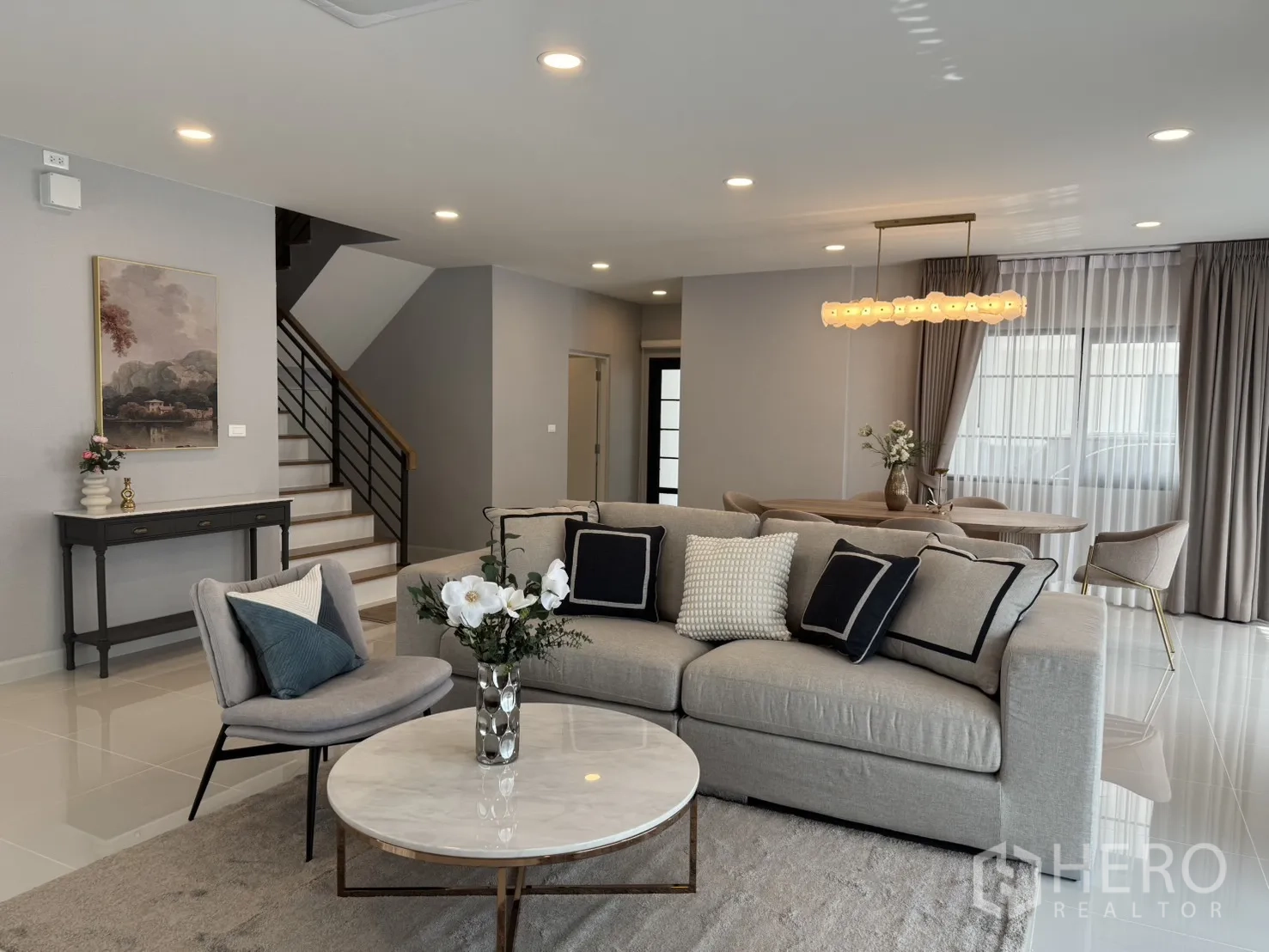 Detached House for rent in Bang Phli, Samut Prakan - Full view of lounge and dining space with staircase, soft gray palette and abundant daylight.