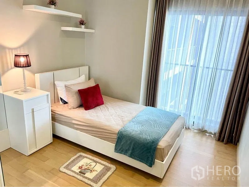 คอนโด ให้เช่าในWatthana, Bangkok - ห้องนอนที่สองอบอุ่น เตียงเดี่ยว โคมไฟหัวเตียง และม่านโปร่งติดระเบียง