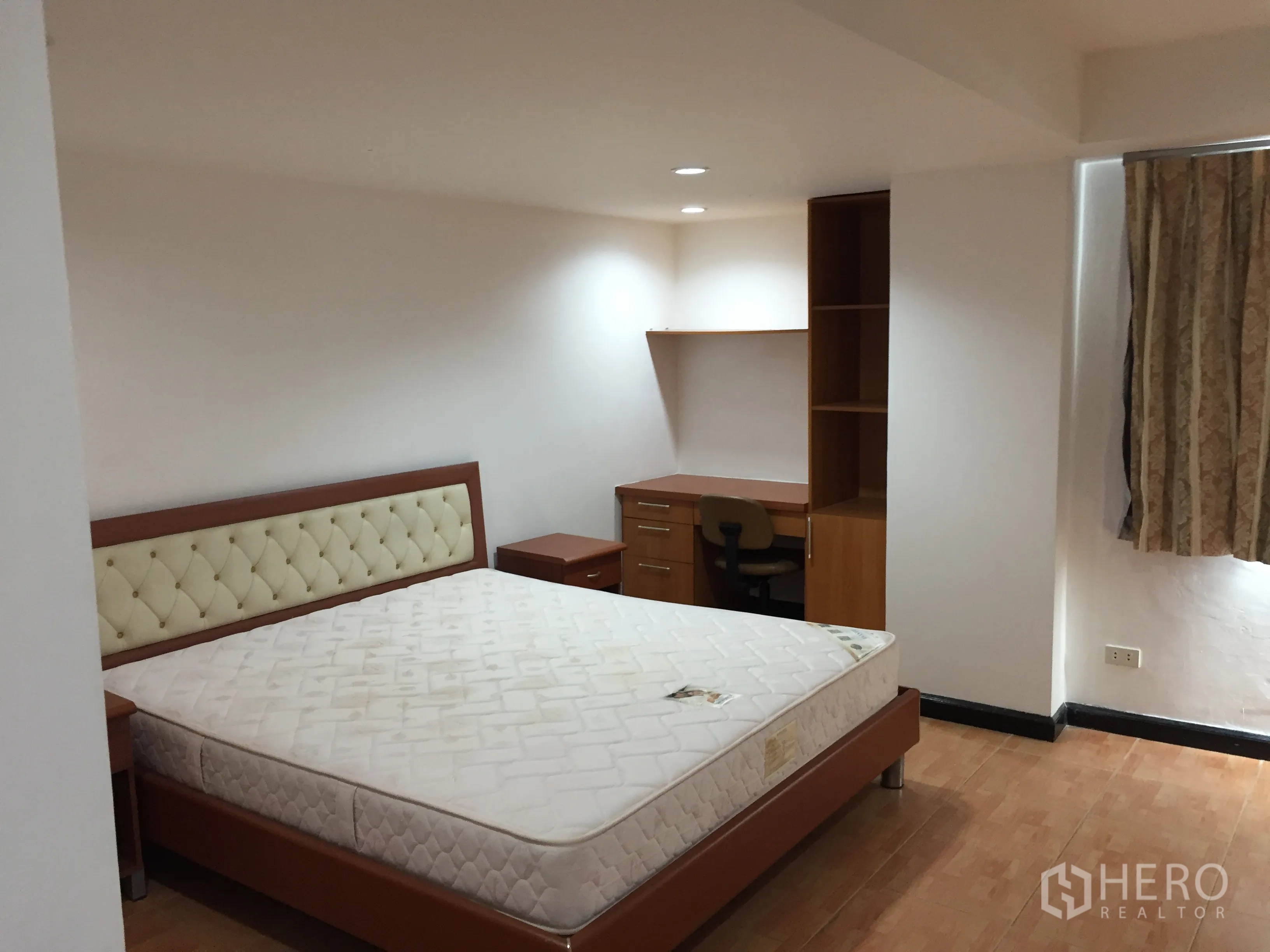 Condominium for rent in Watthana, Bangkok - Bedroom with upholstered headboard, built-in desk and shelving in warm neutral tones.