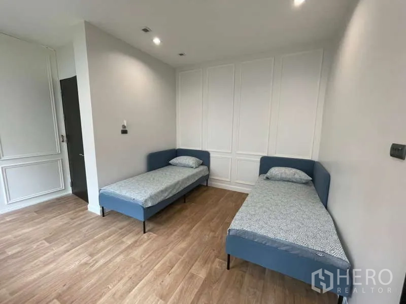 บ้าน ให้เช่าหรือขายในLat Krabang, Bangkok - ห้องนอนแขกมีเตียงเดี่ยวสองเตียง ผนังบัว และพื้นลายไม้