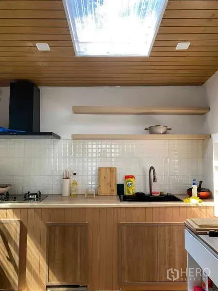 Townhouse for rent or sale in Bang Kapi, Bangkok - Bright modern kitchen with wood cabinets, white tile backsplash and a skylight.