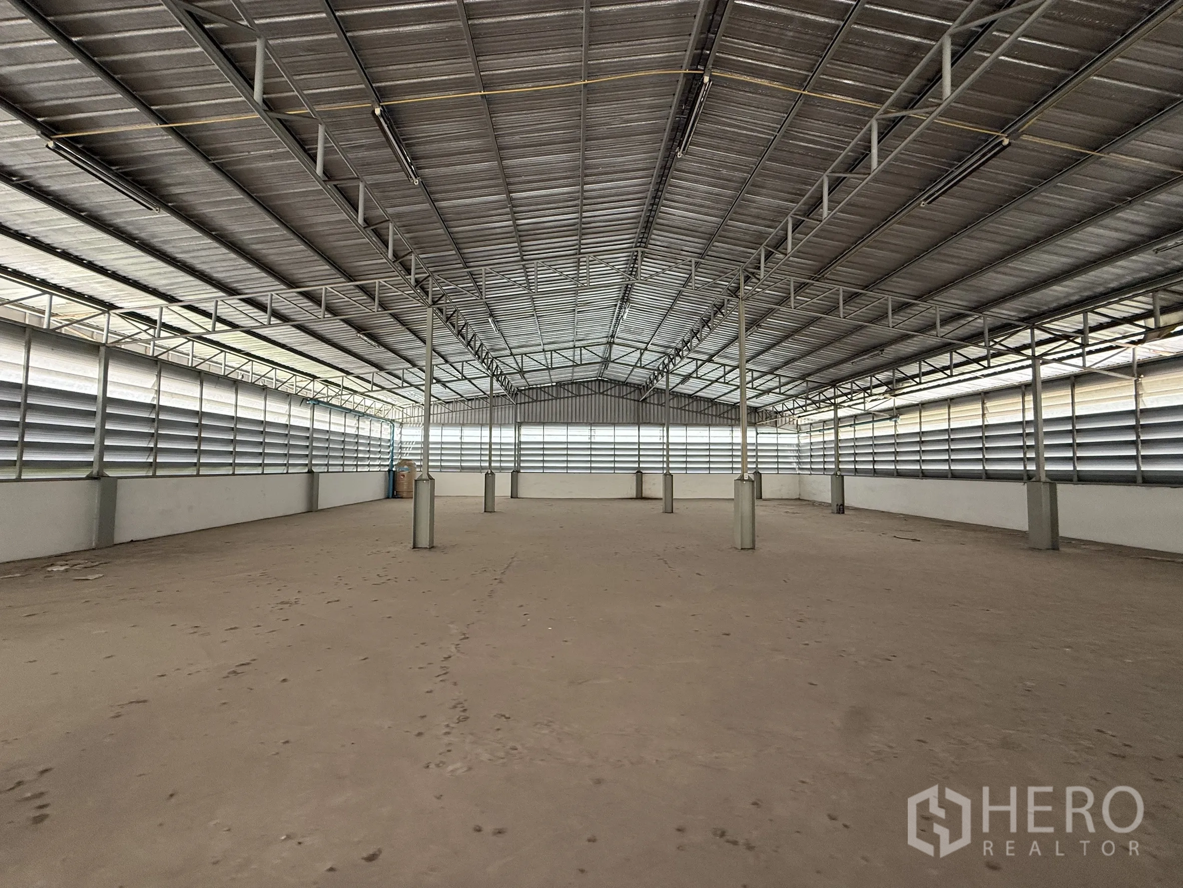 Warehouse for rent in Bueng Kum, Bangkok - Open warehouse hall with metal roof trusses and louvered side ventilation.
