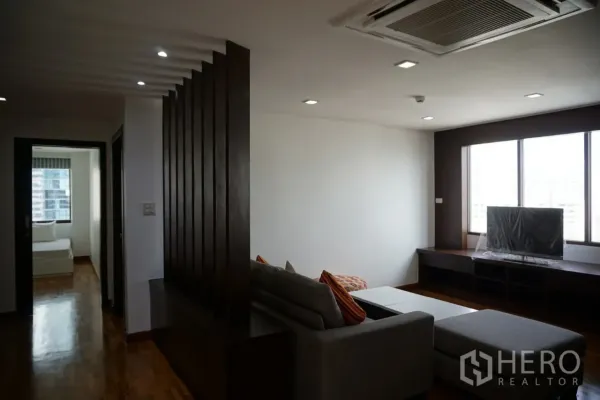 คอนโด ให้เช่าในWatthana, Bangkok - มุมห้องนั่งเล่น โซฟาสีเทา ฉากกั้นไม้ บิลท์อินชั้นวางทีวี ไฟดาวน์ไลท์ และหน้าต่างรับแสง