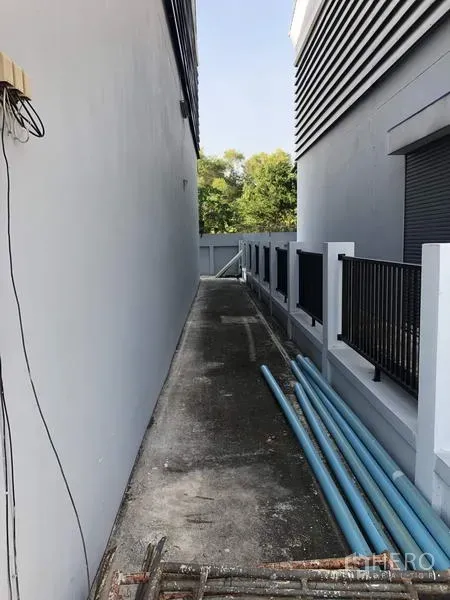 工厂 出租在Lam Luk Ka, Pathum Thani - 侧边服务走道，沿墙设有排水与PVC管线。