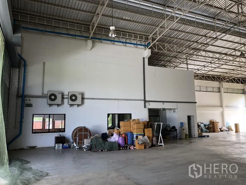Factory for rent or sale in Lat Lum Kaeo, Pathum Thani - Warehouse corner with wall-mounted air conditioners, storage area and steel roof structure.