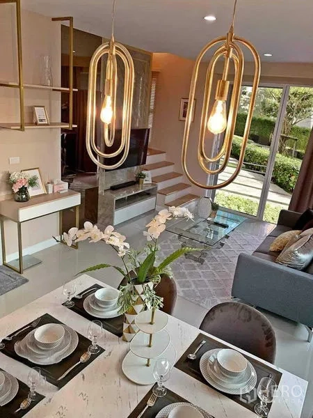 联排别墅 出售在Mueang Nonthaburi, Nonthaburi - 餐区配金色吊灯，俯瞰客厅与花园景观