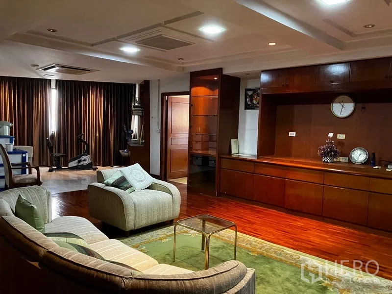 คอนโด ให้เช่าหรือขายในKhlong Toei, Bangkok - โซฟาทรงโค้งหันเข้าตู้บิลท์อินไม้ยาว พร้อมพรมและผ้าม่านทึบ ในห้องนั่งเล่นใหญ่