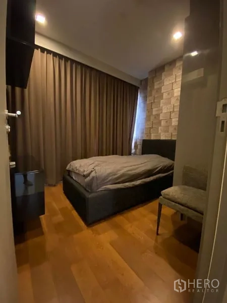 Condominium for rent in Bang Rak, Bangkok - Cozy small bedroom with decorative brick accent wall, curtains, and a single bed.