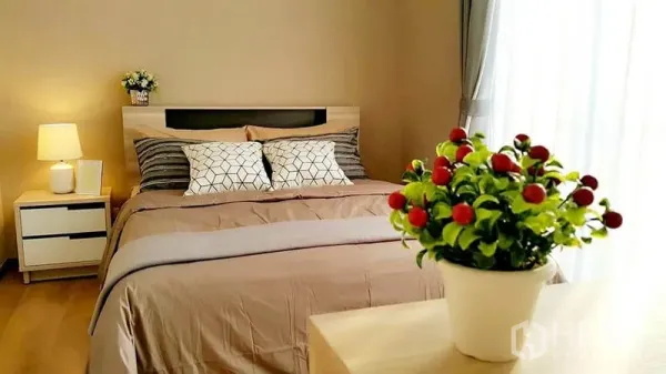 คอนโด ให้เช่าในKhlong Toei, Bangkok - ห้องนอนหลักสว่าง เตียงควีนไซส์ โต๊ะข้างเตียง และม่านโปร่ง