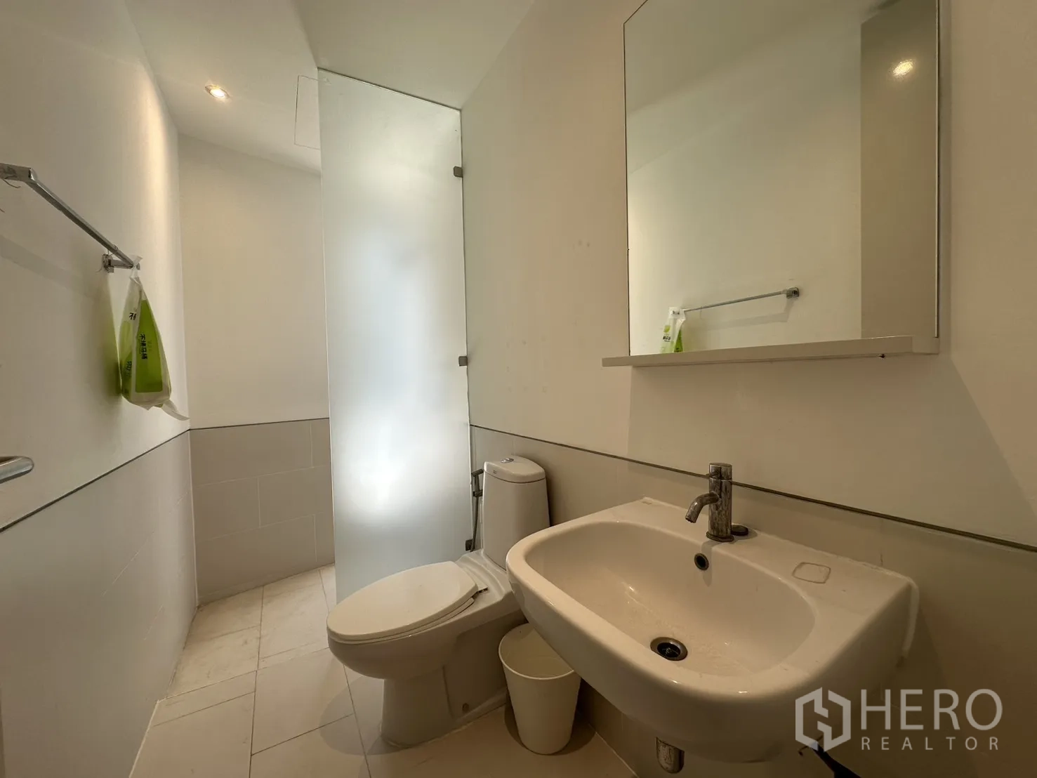 Home Office for rent in Phra Khanong, Bangkok - Clean bathroom with toilet, sink, and a frosted divider.