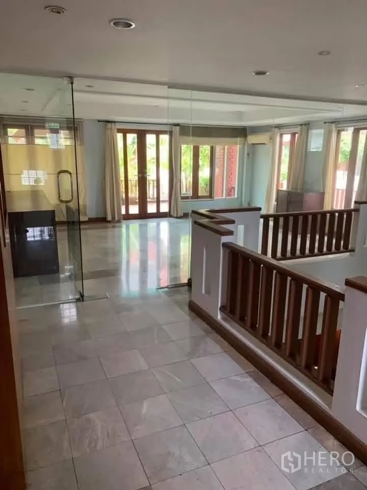 Townhouse for rent in Watthana, Bangkok - Upper landing with glass partition, marble tile, and doors to balconies.