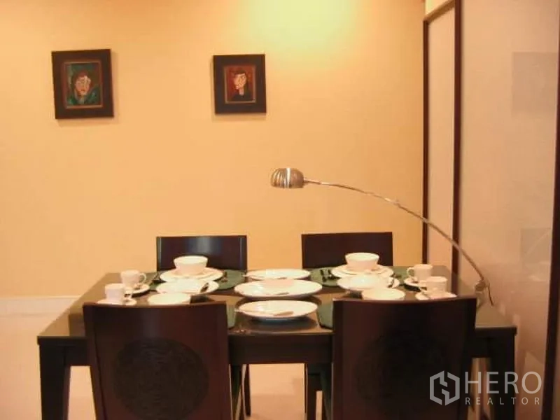 คอนโด ขายในKhlong Toei, Bangkok - มุมทานอาหารสไตล์โมเดิร์น โต๊ะสี่ที่นั่งจัดจานช้อนพร้อม โคมไฟโค้ง และภาพแขวนผนัง