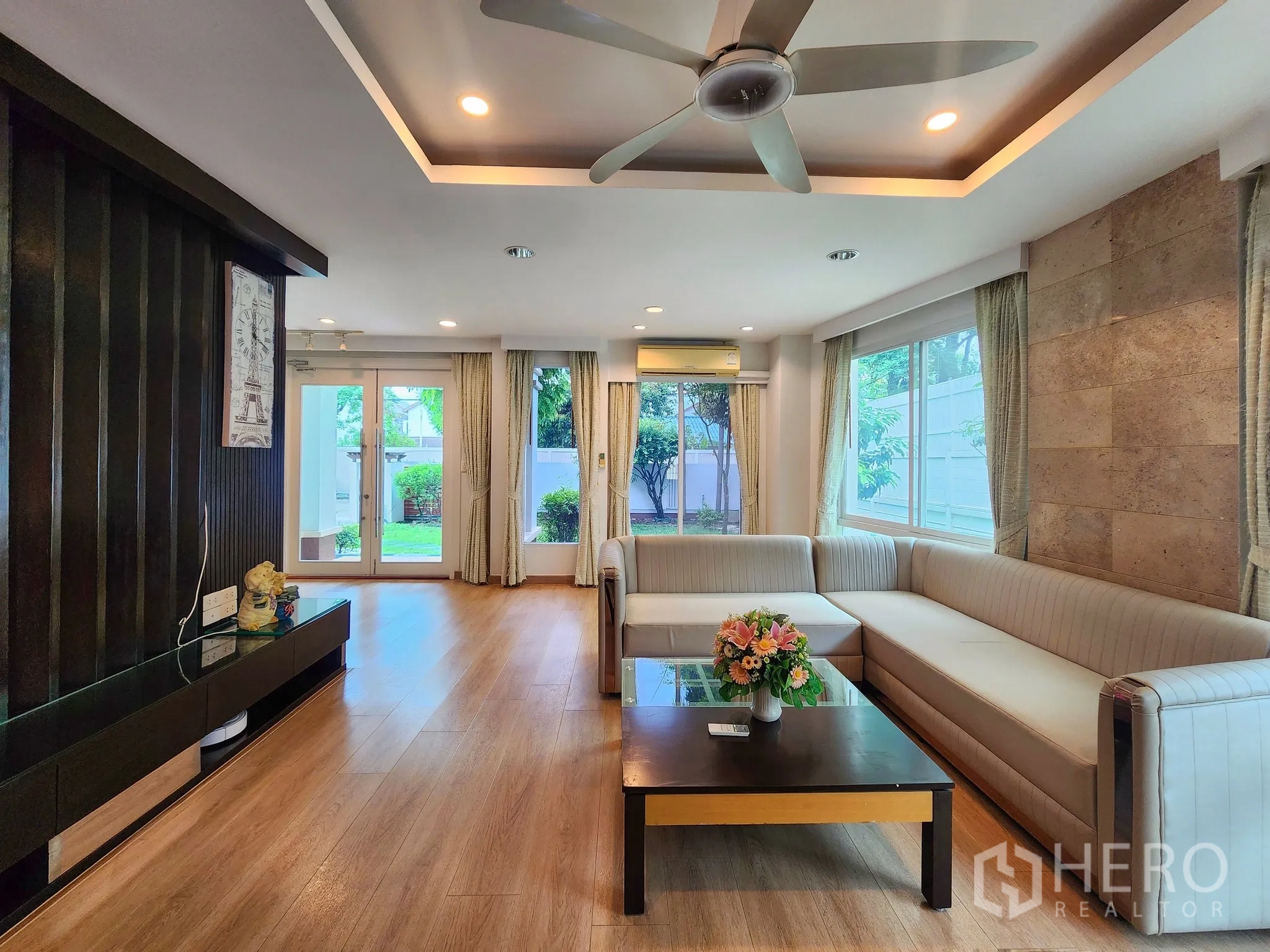 独立式住宅 出租在Bang Kapi, Bangkok - 开放式起居区，转角沙发、影音墙与落地窗。