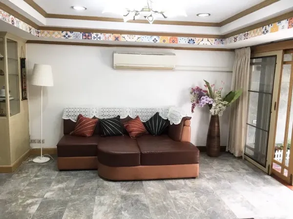 Townhouse for rent in Khlong Toei, Bangkok - Second living area with sectional sofa, air conditioner, floor lamp and sliding glass doors.