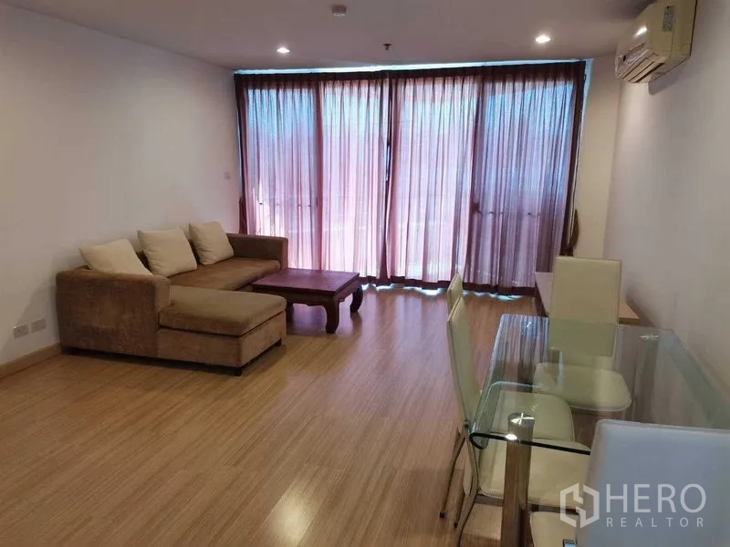 คอนโด ให้เช่าในKhlong Toei, Bangkok - ห้องนั่งเล่นและรับประทานอาหารสว่าง โซฟาเข้ามุม โต๊ะกระจก พื้นไม้ และประตูกระจกสูงเต็มบาน