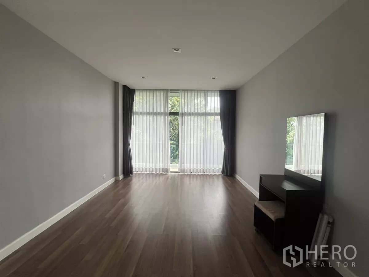 Detached House for sale in Bang Kapi, Bangkok - Bedroom featuring wall-to-wall windows with sheer curtains overlooking greenery.