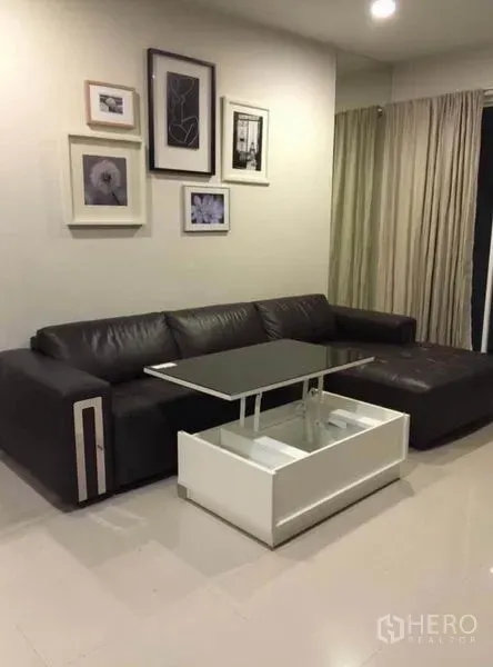 ทาวน์เฮาส์ ให้เช่าในWang Thonglang, Bangkok - ห้องนั่งเล่นอบอุ่น โซฟา L-Shape หนัง โต๊ะกลางยกท็อป กรอบรูปตกแต่งผนัง และผ้าม่านเต็มบาน