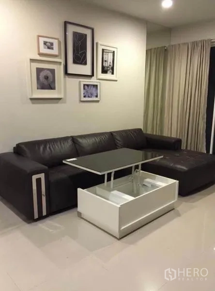 ทาวน์เฮาส์ ให้เช่าในWang Thonglang, Bangkok - ห้องนั่งเล่นอบอุ่น โซฟา L-Shape หนัง โต๊ะกลางยกท็อป กรอบรูปตกแต่งผนัง และผ้าม่านเต็มบาน